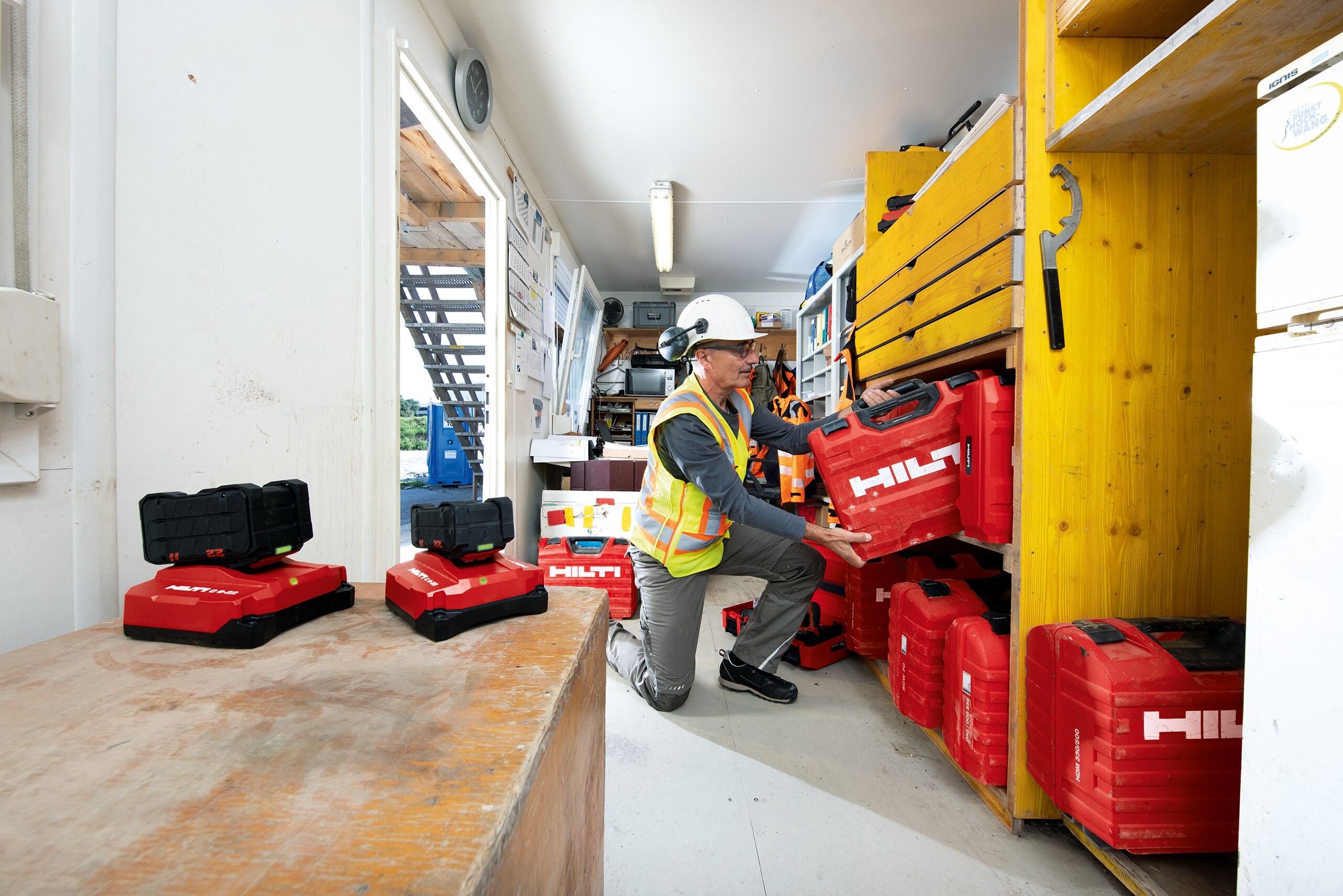 Un gestionnaire de parc d’outils range une boîte à outils Hilti sur une étagère dans un container de chantier 